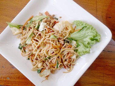 Ahşap masa üzerinde beyaz tabak acılı spagetti