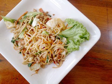 Ahşap masa üzerinde beyaz tabak acılı spagetti