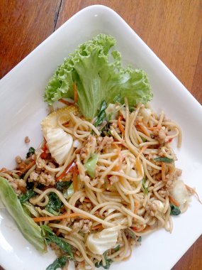 Ahşap masa üzerinde beyaz tabak acılı spagetti