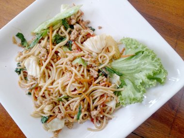 Ahşap masa üzerinde beyaz tabak acılı spagetti