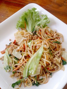 Ahşap masa üzerinde beyaz tabak acılı spagetti