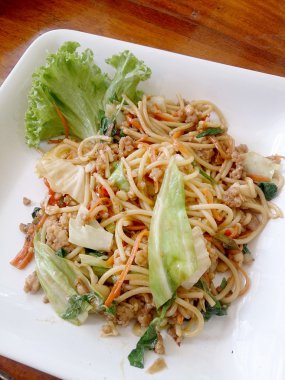 Ahşap masa üzerinde beyaz tabak acılı spagetti