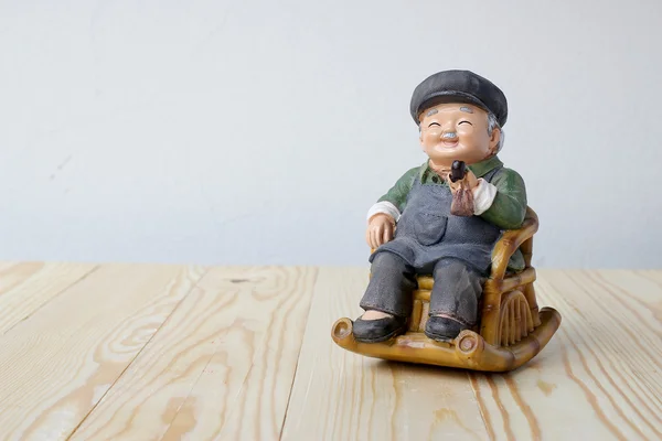 The grandpa in chinese style with cigar siting rocking wood chair.