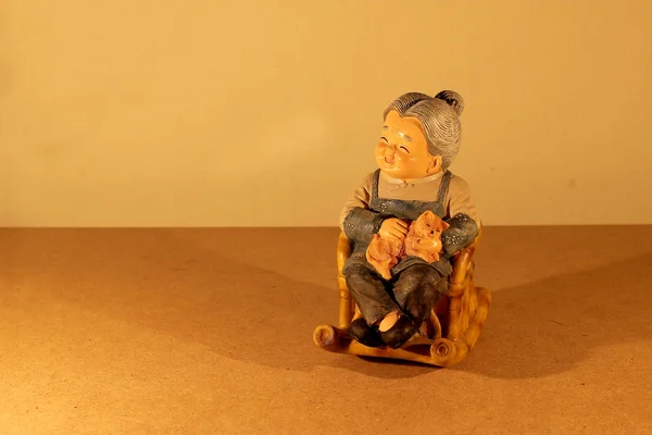 静物摄影与可爱的年长夫妇娃娃选址摇摆竹椅子用木背景黑暗中的蜡烛之光. — 图库照片