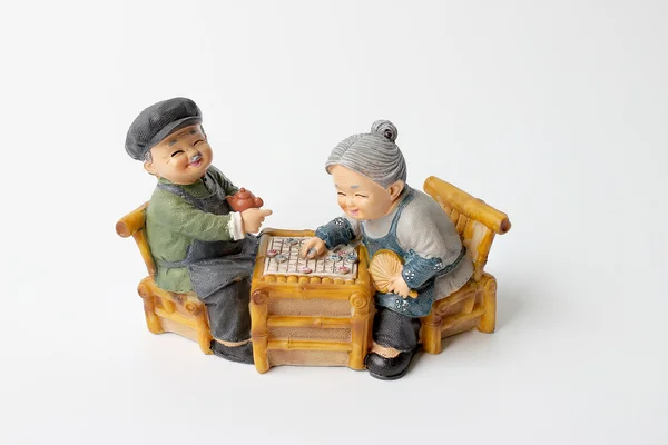 Precioso abuelo muñeca siting balanceo bambú silla con jugar tablero de ajedrez . — Foto de Stock