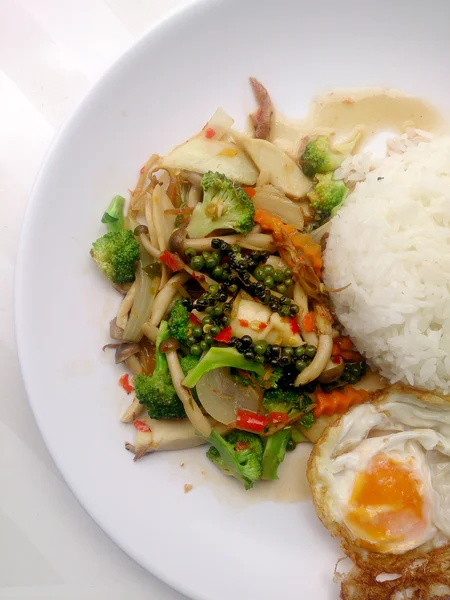 Lada hitam goreng dengan sayuran berwarna-warni dan nasi melati thai & telur goreng dalam hidangan isolasi putih di latar belakang putih. Makanan vegetarian, makanan sehat . — Stok Foto