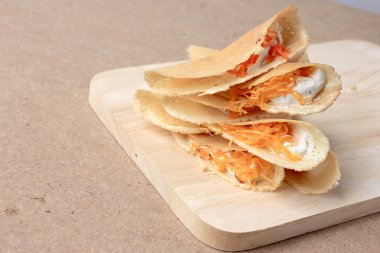 Tayland gözlemesi ahşap arka planda lezzetli atıştırmalıklar, Tayland tatlısı ya da Kanom Buang gibi - Tayland usulü çıtır tart ya da ahşap arka planda ahşap kesim tahtası olan Tayland tatlısı