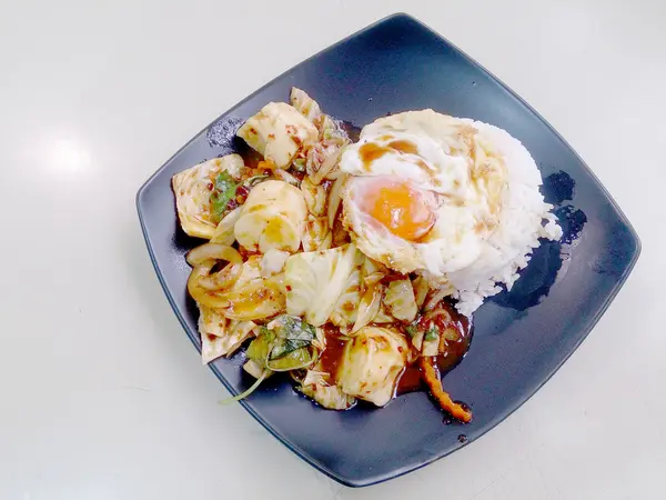 Sekoita paahdetut sekoitetut vihannekset paahdetun chilipastan, paistetun munan ja thaimaalaisen jasmiiniriisin kanssa mustalla lautasella. Kasvisruoka, terveellinen ruoka . — kuvapankkivalokuva