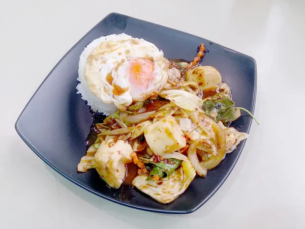 Gebratenes gemischtes Gemüse mit gerösteter Chilipaste, Spiegelei und Thai-Jasminreis auf schwarzem Teller verrühren. Vegetarisches Essen, gesunde Ernährung. — Stockfoto