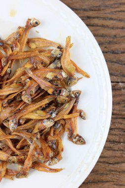 Kızarmış dev yayın balığı ve kızartılmış küçük balıklar (Minnow) geleneksel Tayland tarifleri kırsal ahşap arka planda beyaz tabakta. Tayland 'da popüler, Tayland' ın önemli ihracat ürünü.