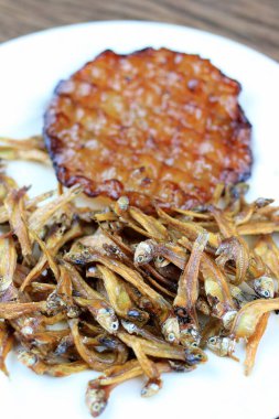 Kızarmış dev yayın balığı ve kızartılmış küçük balıklar (Minnow) geleneksel Tayland tarifleri kırsal ahşap arka planda beyaz tabakta. Tayland 'da popüler, Tayland' ın önemli ihracat ürünü.