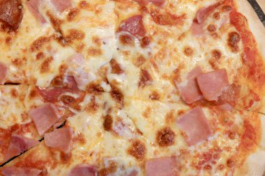 Tahta kesim tahtasında dilimlenmiş peynirli pizza. Yemek için karton kutuda lezzetli İtalyan yemekleri. Parmesanlı fırında pişirilmiş kabuklu ince hamur, gorgonzola, mozzarella, jambon ve peynir.