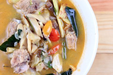 Baharatlı domuz kemiği ve saman mantarı, yabani domates, ahşap masadaki beyaz kasede Tom yum çorbası. Tom Yum Tayland usulü domuz çorbası..