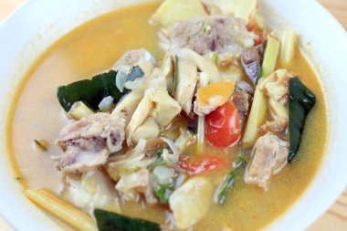Baharatlı domuz kemiği ve saman mantarı, yabani domates, ahşap masadaki beyaz kasede Tom yum çorbası. Tom Yum Tayland usulü domuz çorbası..