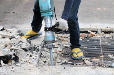 Erkek işçiler, kaldırım boyunca, inşaat alanında, yerel şehir karayolunda beton matkapla beton kazma ve onarım yüzeyi kazmak için elektrikli beton kırıcı kullanıyorlar..