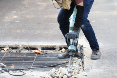 Erkek işçiler, kaldırım boyunca, inşaat alanında, yerel şehir karayolunda beton matkapla beton kazma ve onarım yüzeyi kazmak için elektrikli beton kırıcı kullanıyorlar..