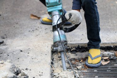 Erkek işçiler, kaldırım boyunca, inşaat alanında, yerel şehir karayolunda beton matkapla beton kazma ve onarım yüzeyi kazmak için elektrikli beton kırıcı kullanıyorlar..