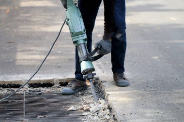 Erkek işçiler, kaldırım boyunca, inşaat alanında, yerel şehir karayolunda beton matkapla beton kazma ve onarım yüzeyi kazmak için elektrikli beton kırıcı kullanıyorlar..