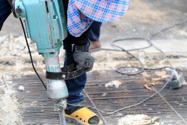 Erkek işçiler, kaldırım boyunca, inşaat alanında, yerel şehir karayolunda beton matkapla beton kazma ve onarım yüzeyi kazmak için elektrikli beton kırıcı kullanıyorlar..