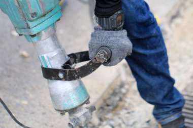 Erkek işçiler, kaldırım boyunca, inşaat alanında, yerel şehir karayolunda beton matkapla beton kazma ve onarım yüzeyi kazmak için elektrikli beton kırıcı kullanıyorlar..