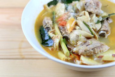 Baharatlı domuz kemiği ve saman mantarı, yabani domates, ahşap masadaki beyaz kasede Tom yum çorbası. Tom Yum Tayland usulü domuz çorbası..