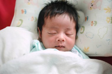 Bir bebeğin yakın çekimi. Yatakta uyumak, yeni doğmuş bebek.