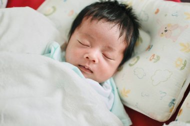 Bir bebeğin yakın çekimi. Yatakta uyumak, yeni doğmuş bebek.