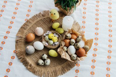 Yüksek açılı, kahverengi ve beyaz tavuk yumurtalarının yeniden kullanılabilir ağ iplik torbasına konulmuş karton bir kutuya konulmuş hali. Sahne, içinde iki tüylü sarı oyuncak civciv ve narin bahar çiçeklerinin bulunduğu küçük bir kuş yuvası ile süslenmiştir.,