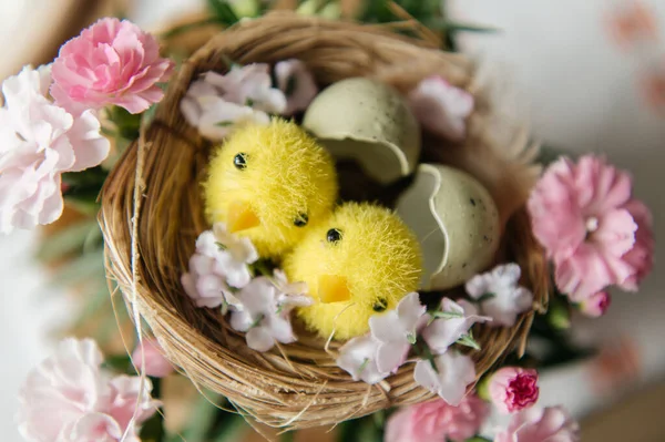 Yumurta kabuklu küçük bir yuvada iki sevimli oyuncak yavrunun yer aldığı neşeli Paskalya 'da hayat devam ediyor. Sahne benekli bıldırcın yumurtaları ve beyaz işlemeli masa örtüsü üzerinde taze pembe karanfil çiçekleriyle çevrilidir. Sıcak, aydınlık ve sıcak bir tatil.