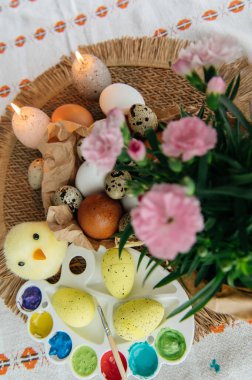 Yüksek açılı, kahverengi ve beyaz tavuk yumurtalarının yeniden kullanılabilir ağ iplik torbasına konulmuş karton bir kutuya konulmuş hali. Sahne, içinde iki tüylü sarı oyuncak civciv ve narin bahar çiçeklerinin bulunduğu küçük bir kuş yuvası ile süslenmiştir.,