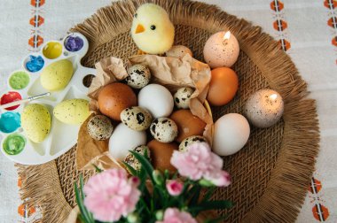 Yüksek açılı, kahverengi ve beyaz tavuk yumurtalarının yeniden kullanılabilir ağ iplik torbasına konulmuş karton bir kutuya konulmuş hali. Sahne, içinde iki tüylü sarı oyuncak civciv ve narin bahar çiçeklerinin bulunduğu küçük bir kuş yuvası ile süslenmiştir.,