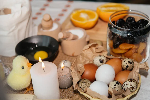 Beyaz ve kahverengi tavuk yumurtalarının karton bir kutuda pamuk iplik torbasına konduğu neşeli bir Paskalya. Kompozisyon, içinde iki tüylü sarı oyuncak civciv ve narin bahar çiçeklerinin bulunduğu küçük bir yuva ile süslenmiş..