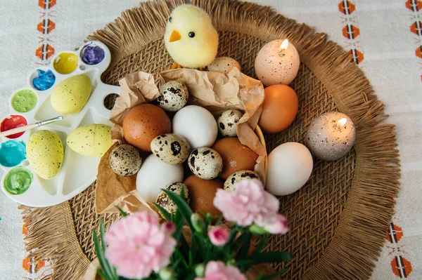 Yüksek açılı, kahverengi ve beyaz tavuk yumurtalarının yeniden kullanılabilir ağ iplik torbasına konulmuş karton bir kutuya konulmuş hali. Sahne, içinde iki tüylü sarı oyuncak civciv ve narin bahar çiçeklerinin bulunduğu küçük bir kuş yuvası ile süslenmiştir.,