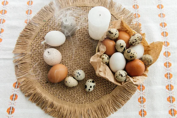 Yüksek açılı, kahverengi ve beyaz tavuk yumurtalarının yeniden kullanılabilir ağ iplik torbasına konulmuş karton bir kutuya konulmuş hali. Sahne, içinde iki tüylü sarı oyuncak civciv ve narin bahar çiçeklerinin bulunduğu küçük bir kuş yuvası ile süslenmiştir.,