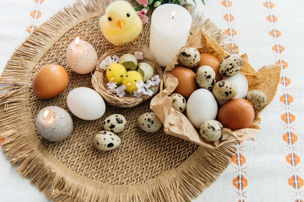Yüksek açılı, kahverengi ve beyaz tavuk yumurtalarının yeniden kullanılabilir ağ iplik torbasına konulmuş karton bir kutuya konulmuş hali. Sahne, içinde iki tüylü sarı oyuncak civciv ve narin bahar çiçeklerinin bulunduğu küçük bir kuş yuvası ile süslenmiştir.,