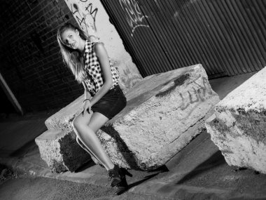 siyah ve beyaz ile sokakta oturan sarışın bir kadın c bacaklar