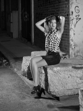 kafasını tutarak sokakta oturan sarışın kadın