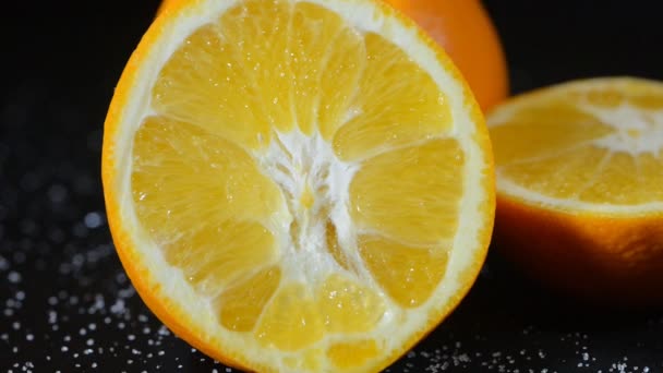 Tangerine cut in half rotates on a black background in white point — Stock Video