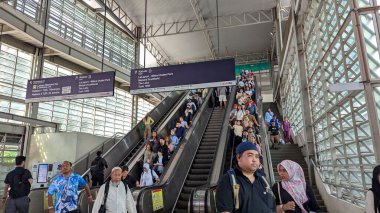 Kuala Lumpur, Malezya-22 Aralık 2025: Malezya 'daki KLIA taşımacılık istasyonu yürüyen merdivenler, yön işareti ve KLIA2 ve KL Sentral platformlarına giden banliyö yolcuları ile meşgul.