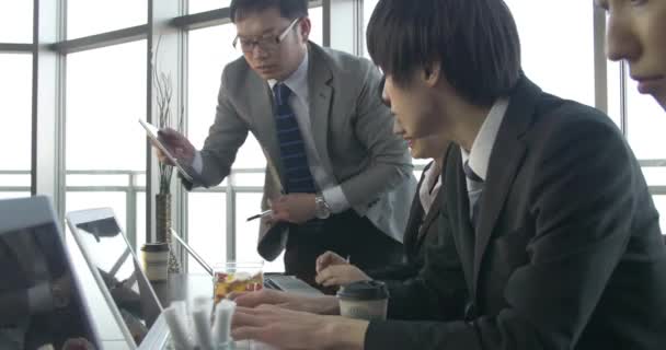 Motivado equipo de trabajo japonés hacer planes juntos comprobado por el jefe de deslizamiento de tiro — Vídeo de stock