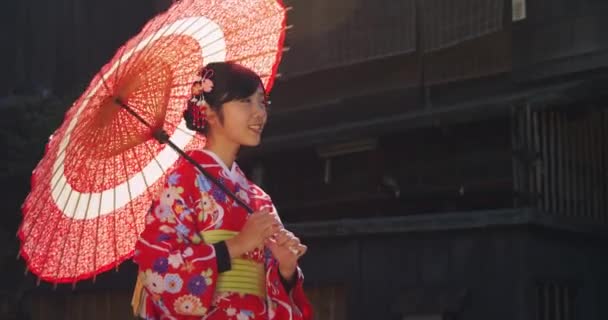 Joven japonés rojo kimono chica vueltas a mirar el cámara puente — Vídeos de Stock