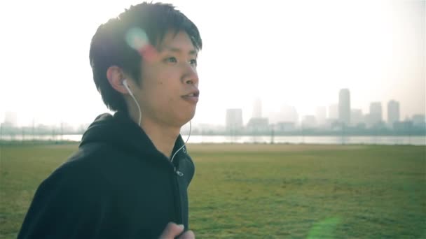 Japanisch fitness mann läuft während hören von musik in osaka, japan steady cam shot — Stockvideo