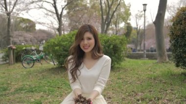 Çim atma oturan güzel Japon kızı havada ağır çekim yapraklar 