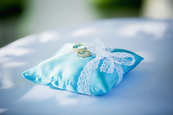 Anéis de casamento no travesseiro azul — Fotografia de Stock