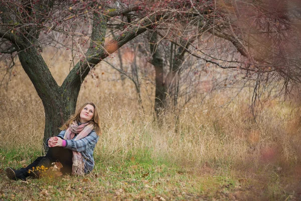 ツリーの下に座っている若い女の子 — ストック写真