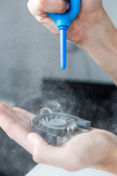 Man blows dust into the laptop fan — Stock Photo, Image