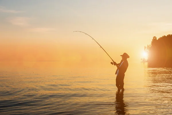 Рыбак на озере на закате — стоковое фото