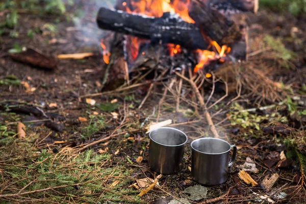 Metal mugs near bonfire — Stock Photo, Image