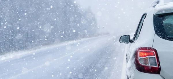 雪に覆われた森を通って冬の道路上の白い車 — ストック写真