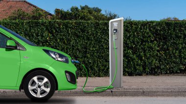 Green electric car with a charging station clipart